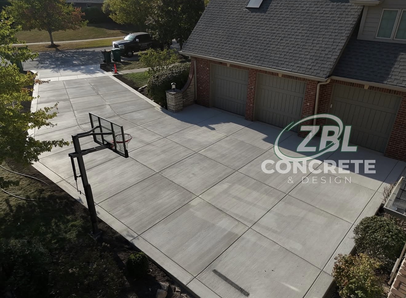 Large concrete driveway with basketball court by ZBL Concrete & Design
