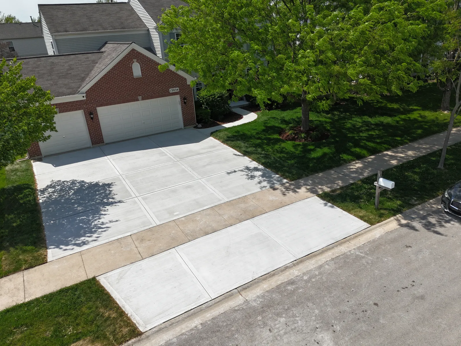 Concrete driveway at red brick home — aerial drone view