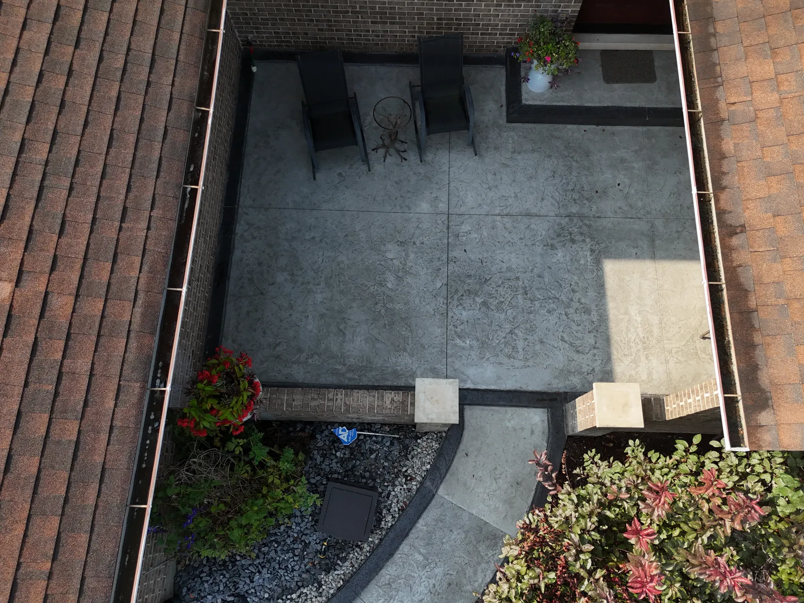 Intimate courtyard concrete patio between rooflines — aerial