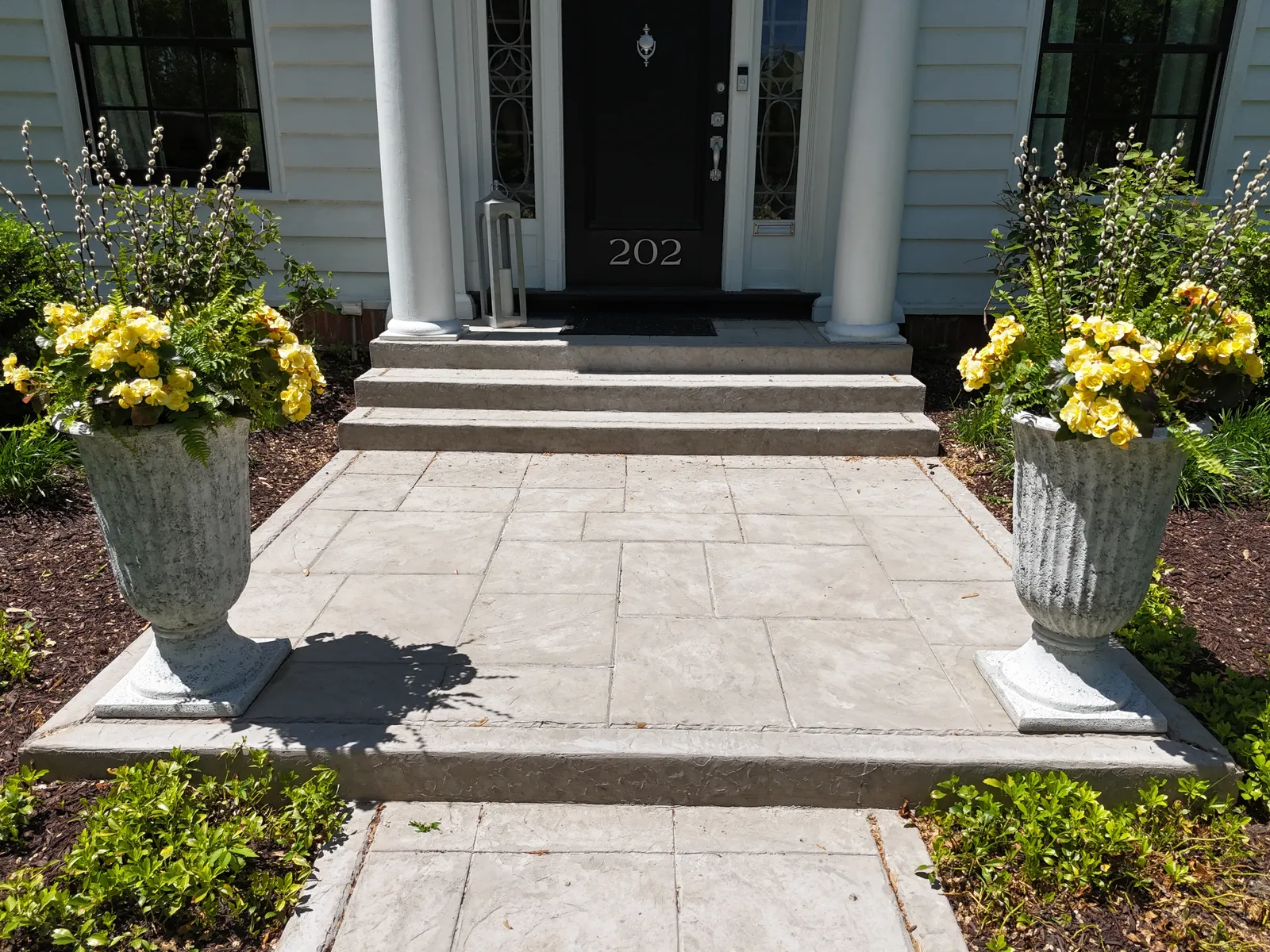 Stamped concrete entry stoop with decorative urns and flowers
