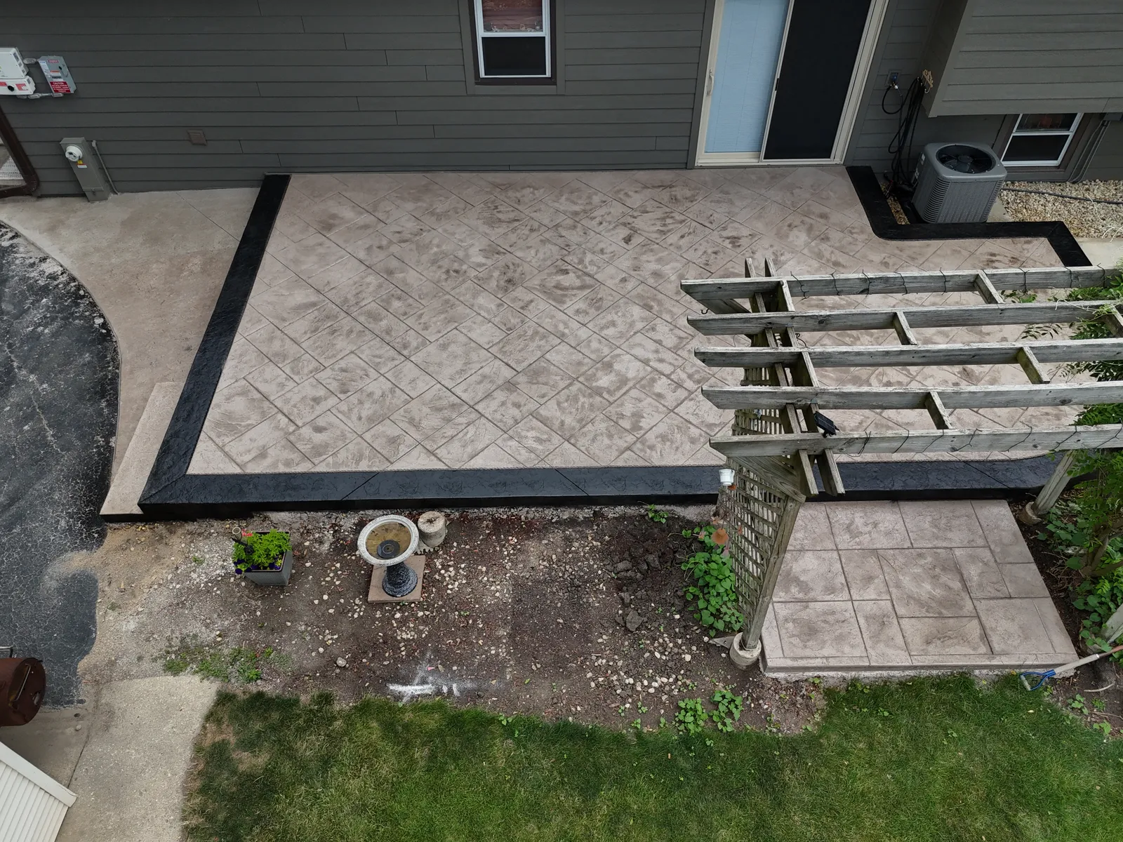 Stamped concrete patio connecting to deck and pergola — overhead