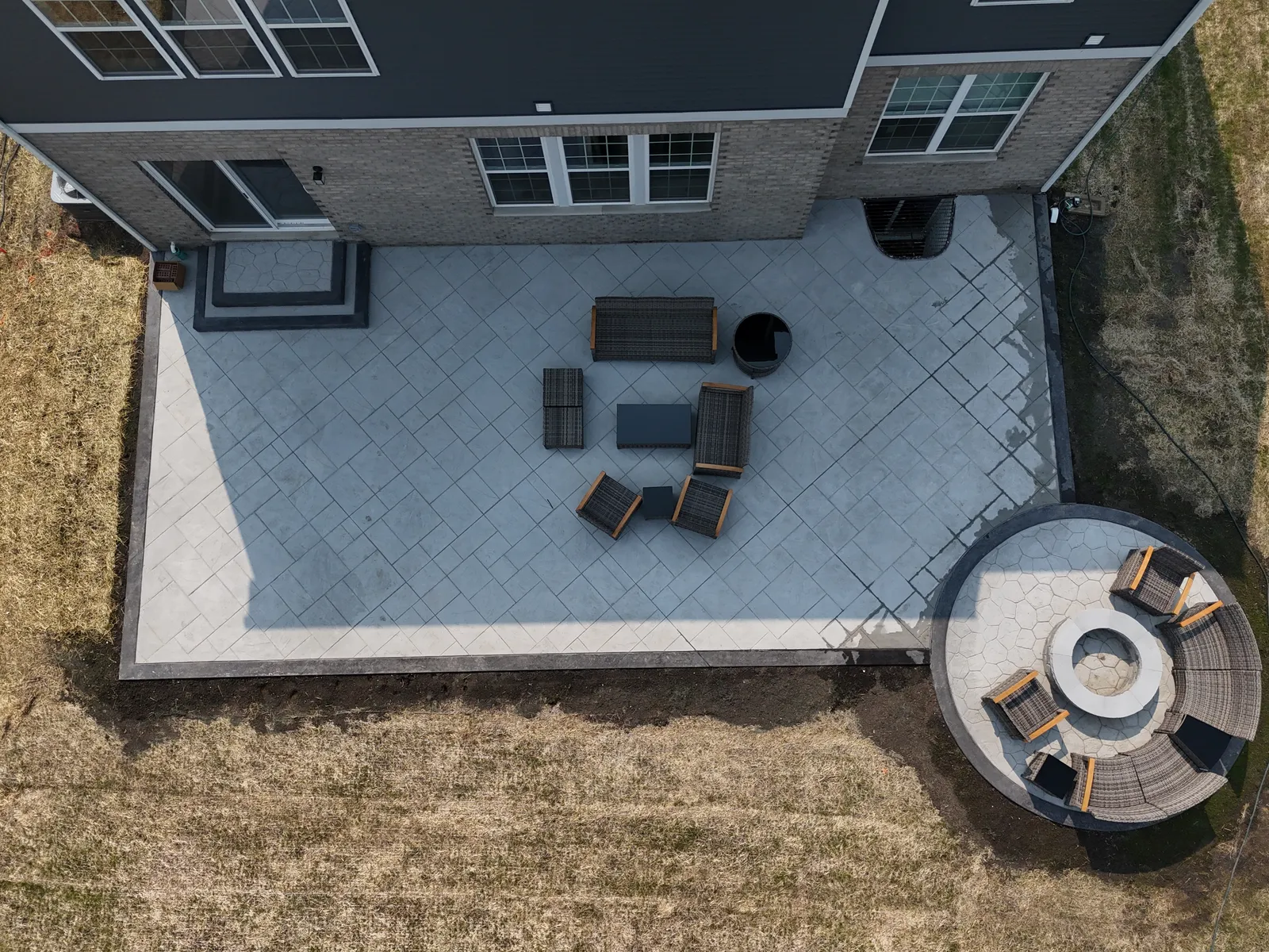 Stamped patio with circular fire pit pad — aerial drone view