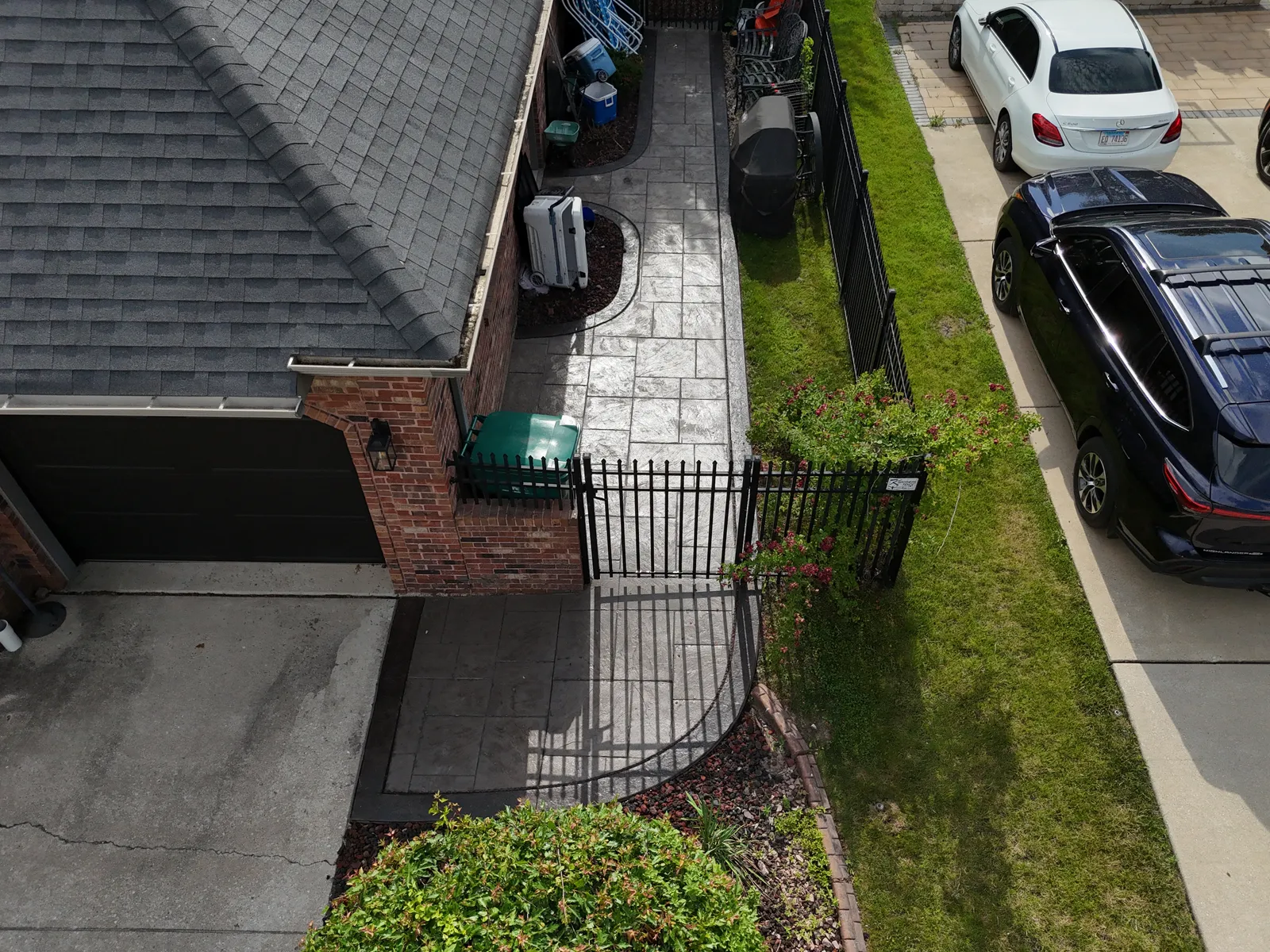 Stamped concrete side patio and walkway overview with iron gate