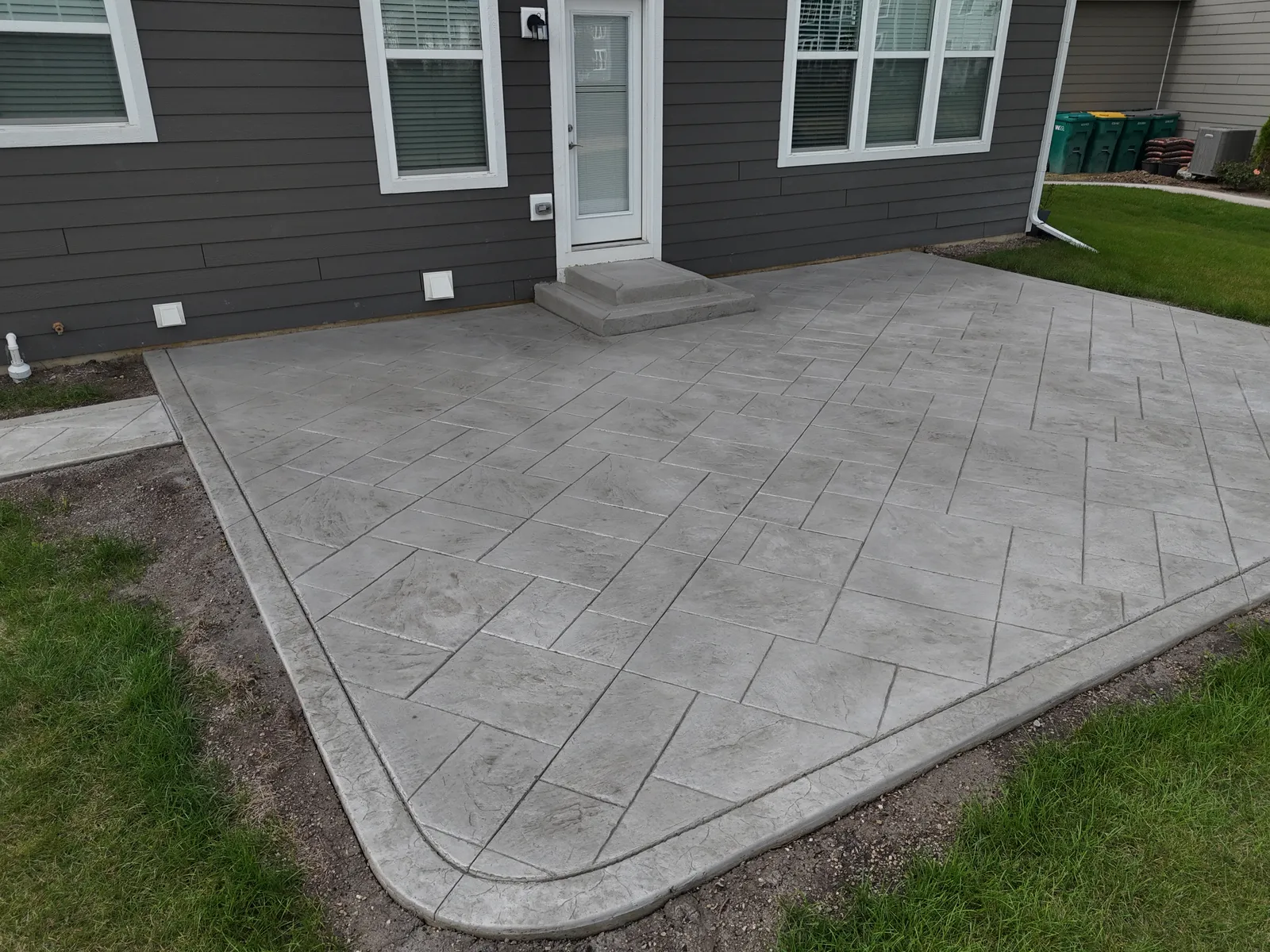 Stamped concrete patio with step landing at dark gray home
