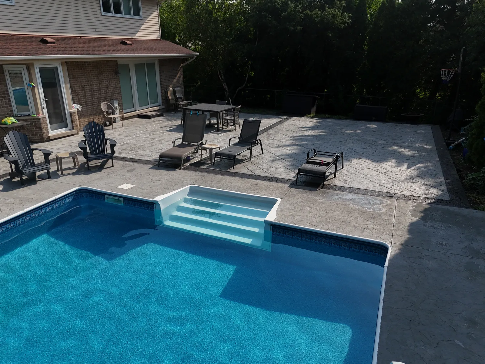 Stamped concrete pool deck with lounge furniture — aerial